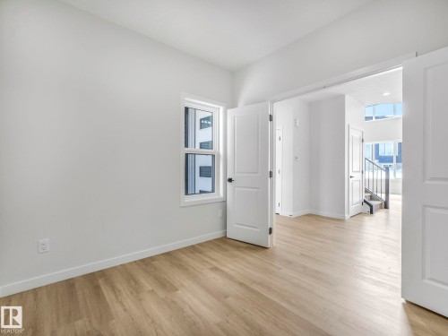 Light wood-finish flooring with crisp white baseboards and walls - 239 Kinglet Boulevard Nw, Edmonton, AB - Indoor Photo Showing Other Room