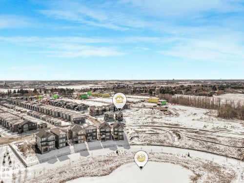 Aerial overview featuring a residential development bordered by open land and a frozen body of water - 239 Kinglet Boulevard Nw, Edmonton, AB - Outdoor With View