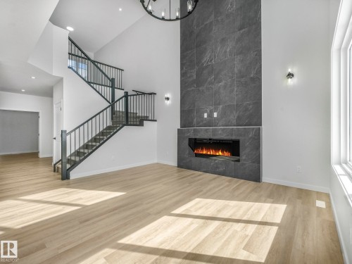 Expansive open-concept living space featuring soaring vaulted ceilings, abundant natural light from oversized windows, and wide-plank wood-finish flooring throughout - 239 Kinglet Boulevard Nw, Edmonton, AB - Indoor With Fireplace