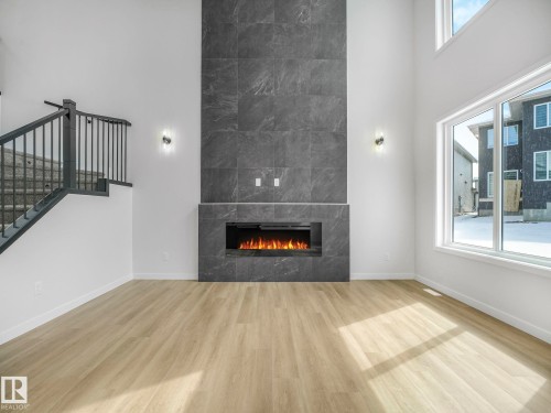 Two-story living area featuring a full-height fireplace with dark stone-finish tiles and an electric insert - 239 Kinglet Boulevard Nw, Edmonton, AB - Indoor With Fireplace