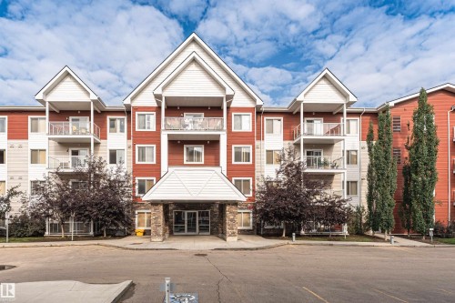 Contemporary multi-unit residential building featuring a striking gabled roofline with peaked dormers, warm brick and horizontal siding exterior, and multiple private balconies across three stories - #310 2229 44 Av Nw, Edmonton, AB - Outdoor With Balcony With Facade