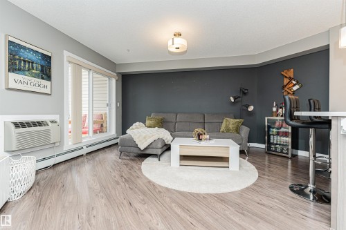Spacious primary living area featuring wood-finish flooring, recessed ceiling lighting, and a neutral color palette - #310 2229 44 Av Nw, Edmonton, AB - Indoor
