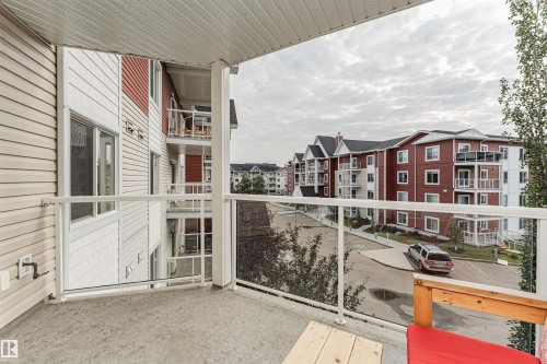 Private balcony featuring glass panel railing, concrete flooring, and surrounding building architecture - #310 2229 44 Av Nw, Edmonton, AB - Outdoor With Balcony With Exterior