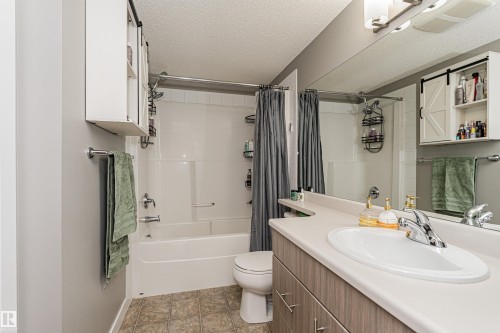 Spa-inspired bathroom featuring a ceramic soaking tub with integrated shower surround, dual-sink vanity with wood-finish cabinetry and white countertop, recessed medicine cabinets with shelving, tile flooring, and chrome fixtures throughout - #310 2229 44 Av Nw, Edmonton, AB - Indoor Photo Showing Bathroom