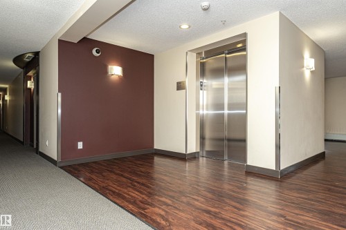 Stainless steel elevator with wood-finish flooring - #310 2229 44 Av Nw, Edmonton, AB - Indoor Photo Showing Other Room