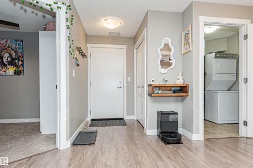 Welcoming foyer featuring wood-finish flooring, recessed ceiling lighting, and white six-panel doors - #310 2229 44 Av Nw, Edmonton, AB - Indoor Photo Showing Laundry Room