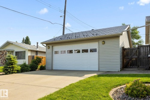 Detached garage with horizontal siding, a paneled overhead door, and a shingled roof - 9503 54 Street Nw, Edmonton, AB - Outdoor