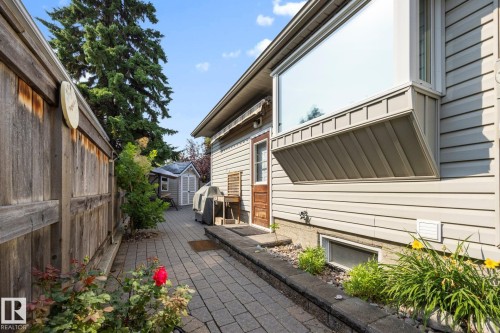 Paved walkway leading to a rear entrance, featuring a large bay window with siding exterior and a wooden fence - 9503 54 Street Nw, Edmonton, AB - Outdoor With Exterior