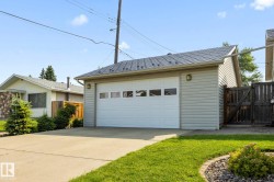 Detached garage with horizontal siding, a paneled overhead door, and a shingled roof - 