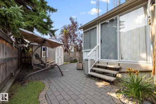 Patio area featuring paver flooring, a wooden privacy fence, a storage shed, and direct access to the interior via sliding glass doors - 9503 54 Street Nw, Edmonton, AB - Outdoor With Exterior