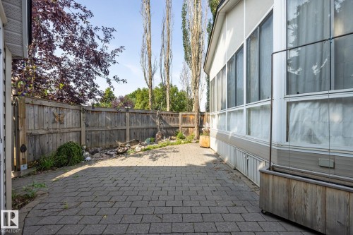 Paved patio area, wood fencing, and a white-sided structure with multiple windows - 9503 54 Street Nw, Edmonton, AB - Outdoor With Exterior