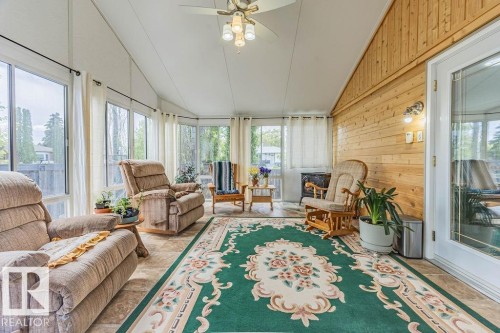 Sunroom with vaulted ceiling and extensive window line - 9503 54 Street Nw, Edmonton, AB - Indoor Photo Showing Living Room With Fireplace
