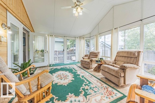 Sunroom featuring extensive window panels, vaulted ceiling, wood-finish flooring, and a ceiling fan with integrated lighting - 9503 54 Street Nw, Edmonton, AB - Indoor