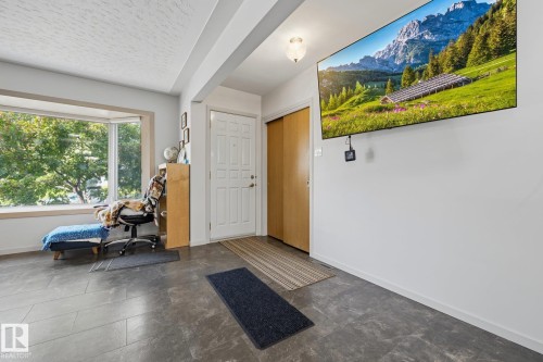Bright entryway flooded with natural light from expansive windows, featuring polished concrete flooring, white interior doors, wood-finish cabinetry, and recessed ceiling lighting - 9503 54 Street Nw, Edmonton, AB - Indoor Photo Showing Other Room