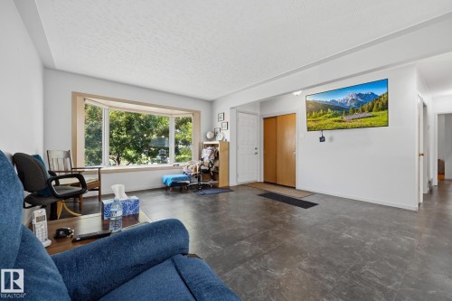 Spacious room with a large bay window, durable flooring, and a built-in closet with bi-fold doors - 9503 54 Street Nw, Edmonton, AB - Indoor