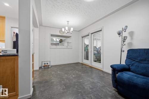 Spacious open-concept living area with slate-finish flooring, recessed ceiling lighting, and glass sliding doors opening to outdoor space - 9503 54 Street Nw, Edmonton, AB - Indoor