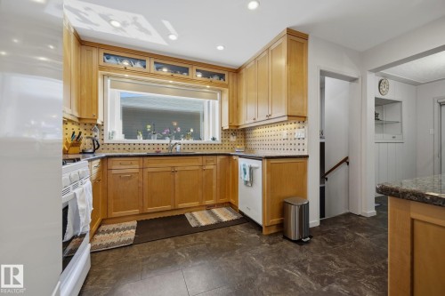 Kitchen featuring wood cabinetry, a large window, recessed lighting, tile flooring, and a built-in dishwasher - 9503 54 Street Nw, Edmonton, AB - Indoor Photo Showing Kitchen