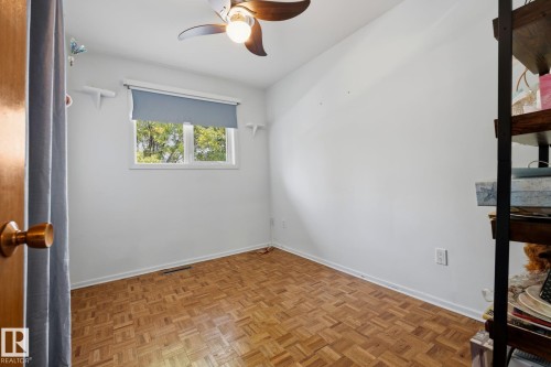 Wood-finish parquet flooring, ceiling-mounted fan with integrated lighting, and a window with a roller shade - 9503 54 Street Nw, Edmonton, AB - Indoor Photo Showing Other Room