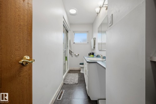 Bathroom with tile flooring, vanity with integrated sink, wall-mounted mirror, and round ceiling light fixture - 9503 54 Street Nw, Edmonton, AB - Indoor Photo Showing Bathroom