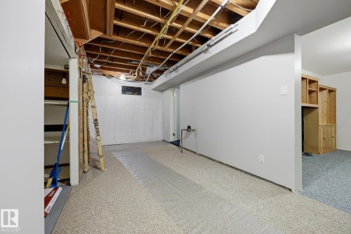 Spacious finished basement featuring exposed wood-beam ceiling, neutral carpet flooring, white drywall construction, and abundant natural light from recessed ceiling fixtures - 9503 54 Street Nw, Edmonton, AB - Indoor Photo Showing Basement