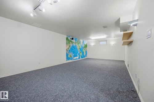 Spacious room with gray carpeting, track lighting, and a window for natural light - 9503 54 Street Nw, Edmonton, AB - Indoor Photo Showing Other Room