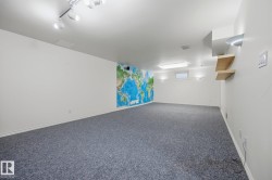 Spacious room with gray carpeting, track lighting, and a window for natural light - 