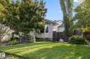 Expansive front yard featuring a manicured lawn, mature trees, and landscaping elements - 9503 54 Street Nw, Edmonton, AB 