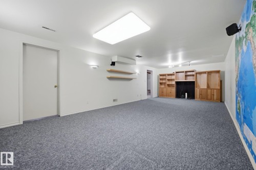 Spacious recreational room featuring polished concrete flooring, recessed ceiling lighting, and built-in wooden cabinetry and shelving - 9503 54 Street Nw, Edmonton, AB - Indoor Photo Showing Other Room