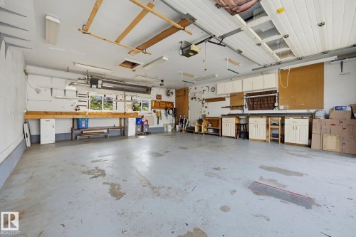 Spacious garage with multiple built-in workstations, overhead cabinetry, and fluorescent lighting - 9503 54 Street Nw, Edmonton, AB - Indoor Photo Showing Garage