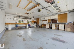 Spacious garage with multiple built-in workstations, overhead cabinetry, and fluorescent lighting - 