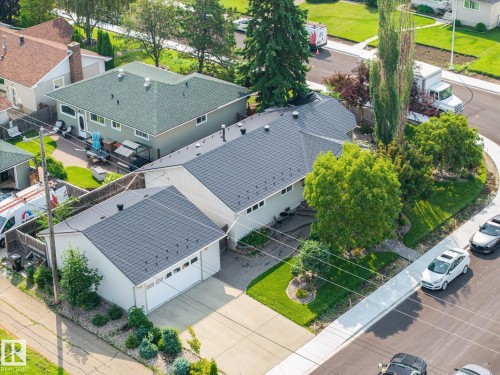 Paved driveway leading to an attached garage, landscaped front yard with mature trees, and a gray shingle roof - 9503 54 Street Nw, Edmonton, AB - Outdoor