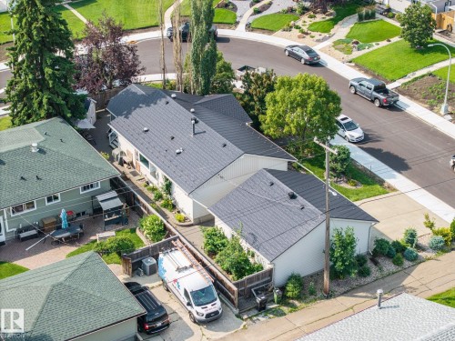 Modern residence featuring a dark charcoal composite roof, clean white exterior siding, and mature landscaping with tall columnar trees - 9503 54 Street Nw, Edmonton, AB - Outdoor