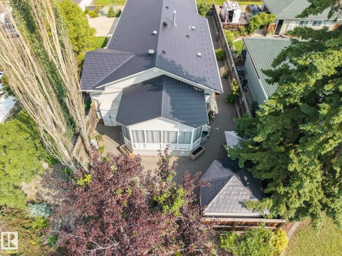 Patio area featuring paver stone hardscaping, mature trees, and an enclosed sunroom - 9503 54 Street Nw, Edmonton, AB - Outdoor