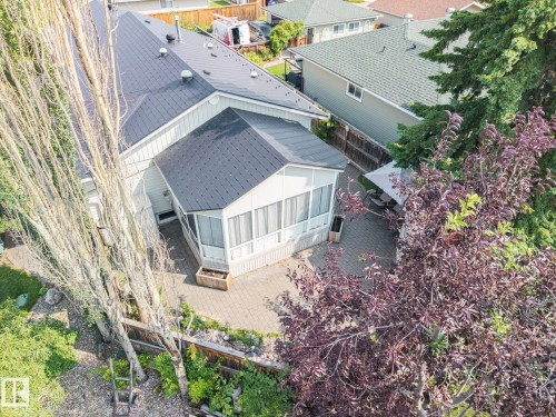 Aerial view showcasing a modern residence with a dark-shingle pitched roof, white exterior trim, and a paved patio area - 9503 54 Street Nw, Edmonton, AB - Outdoor