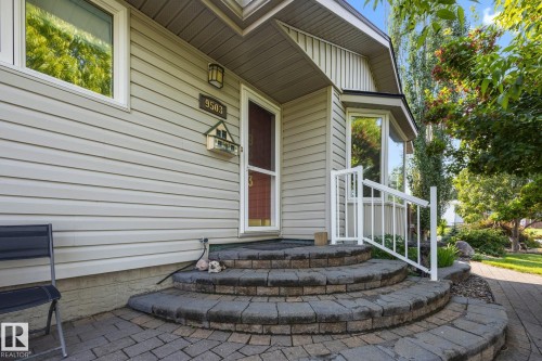 Welcoming front entry featuring a curved paver patio with dimensional stone borders, white railing, and siding exterior accented by landscaped greenery - 9503 54 Street Nw, Edmonton, AB - Outdoor With Exterior