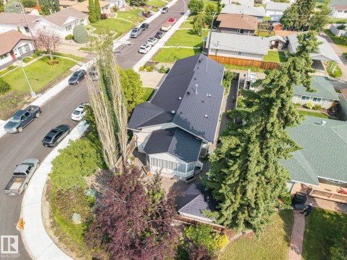 Modern residence featuring a striking black pitched roof, mature landscaping with evergreen and ornamental trees, and a curved driveway approach - 9503 54 Street Nw, Edmonton, AB - Outdoor With View