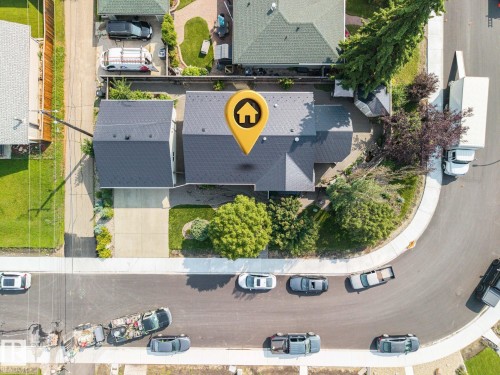 Aerial view showcasing this residential property featuring a dark-shingle roof, manicured front lawn with mature landscaping, paved driveway, and tree-lined street frontage in an established neighborhood setting - 9503 54 Street Nw, Edmonton, AB - Outdoor