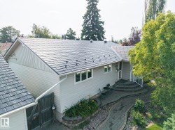 Contemporary home showcasing a freshly installed slate-colored asphalt shingle roof, white vertical siding exterior, and multi-pane windows - 