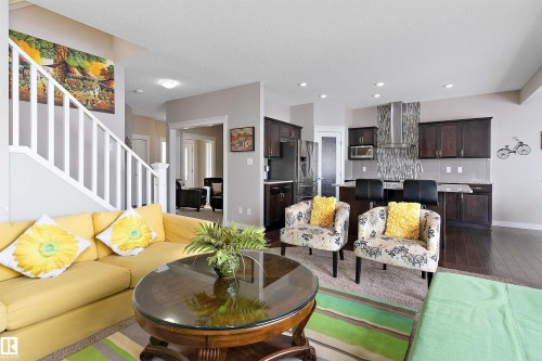 Open-concept living space featuring wood-finish flooring, a kitchen island with seating, a stainless steel range hood, and dark wood cabinetry - 1312 26 Avenue Nw, Edmonton, AB - Indoor Photo Showing Living Room