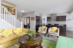 Open-concept living space featuring wood-finish flooring, a kitchen island with seating, a stainless steel range hood, and dark wood cabinetry - 