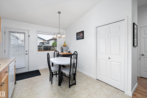 Kitchen dining area featuring neutral tile flooring, a window, a single exterior door, light wood-finish cabinetry, and a bi-fold closet - 3344 24 Avenue Nw, Edmonton, AB - Indoor Photo Showing Dining Room