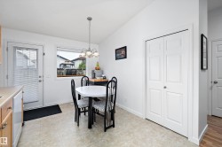 Kitchen dining area featuring neutral tile flooring, a window, a single exterior door, light wood-finish cabinetry, and a bi-fold closet - 