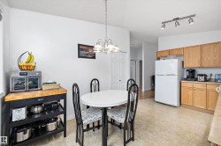 Kitchen and dining area featuring light wood-finish cabinetry, a white refrigerator, and a track light fixture - 