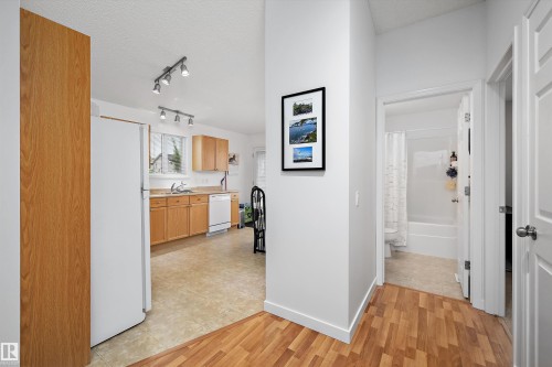 Kitchen with wood-finish flooring, light wood cabinetry, and white appliances - 3344 24 Avenue Nw, Edmonton, AB - Indoor