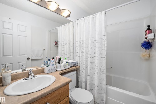 Bathroom featuring a single vanity with an integrated sink, a wood-finish cabinet, and a beige countertop - 3344 24 Avenue Nw, Edmonton, AB - Indoor Photo Showing Bathroom
