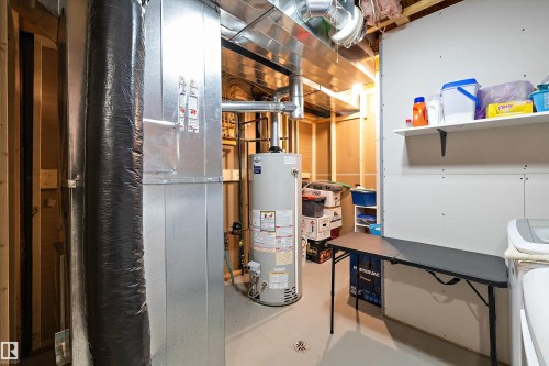 Utility area featuring a water heater, furnace, exposed ductwork, and unfinished wall framing - 3344 24 Avenue Nw, Edmonton, AB - Indoor Photo Showing Basement