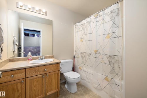 Bathroom featuring a wood-finish vanity with an integrated sink, a large mirror, and a combination tub and shower - 3344 24 Avenue Nw, Edmonton, AB - Indoor Photo Showing Bathroom