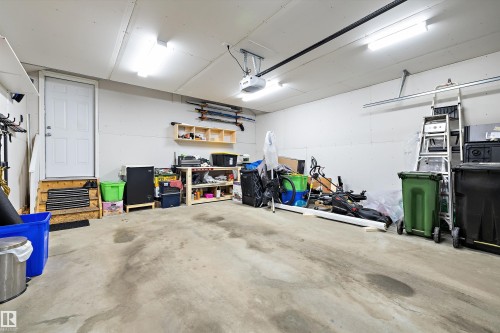 Spacious garage featuring concrete flooring, white drywall, and overhead fluorescent lighting - 3344 24 Avenue Nw, Edmonton, AB - Indoor Photo Showing Garage