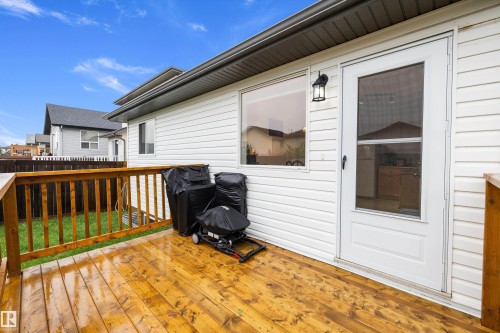 Wood-finish deck with a natural wood railing, white vinyl siding, and a glass-paneled exterior door - 3344 24 Avenue Nw, Edmonton, AB - Outdoor With Deck Patio Veranda With Exterior