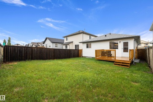 Expansive grassy yard featuring a private wood fence, a large wood deck, and white siding - 3344 24 Avenue Nw, Edmonton, AB - Outdoor With Deck Patio Veranda